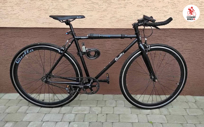 Czarny rower miejski singlespeed oparty o ścianę budynku.